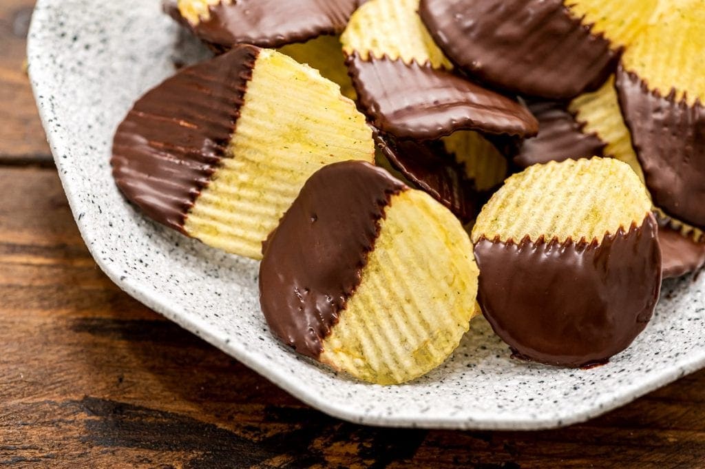 Light colored plate with chocolate covered potato chips stacked on it.