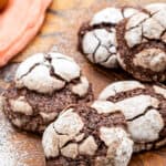 Wooden board with Chocolate Crinkle Cookies stacked on it