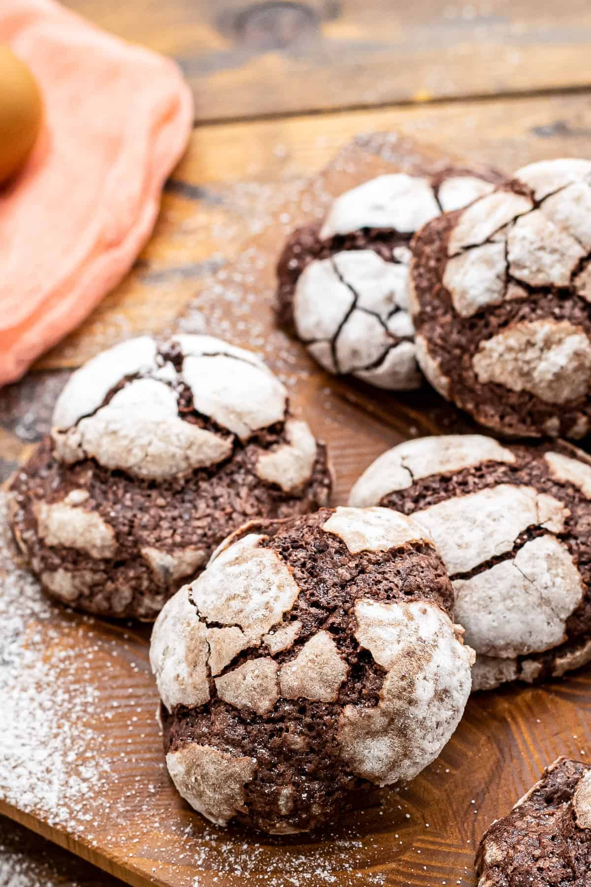 Wooden board with Chocolate Crinkle Cookies stacked on it