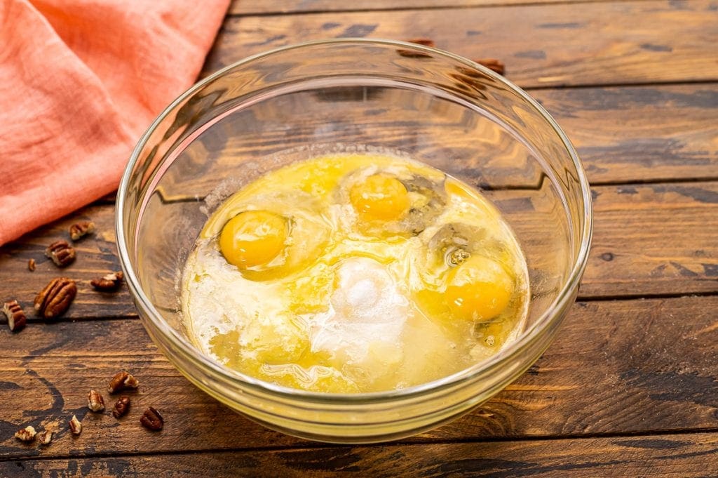 Glass bowl with eggs and sugar in it before mixing