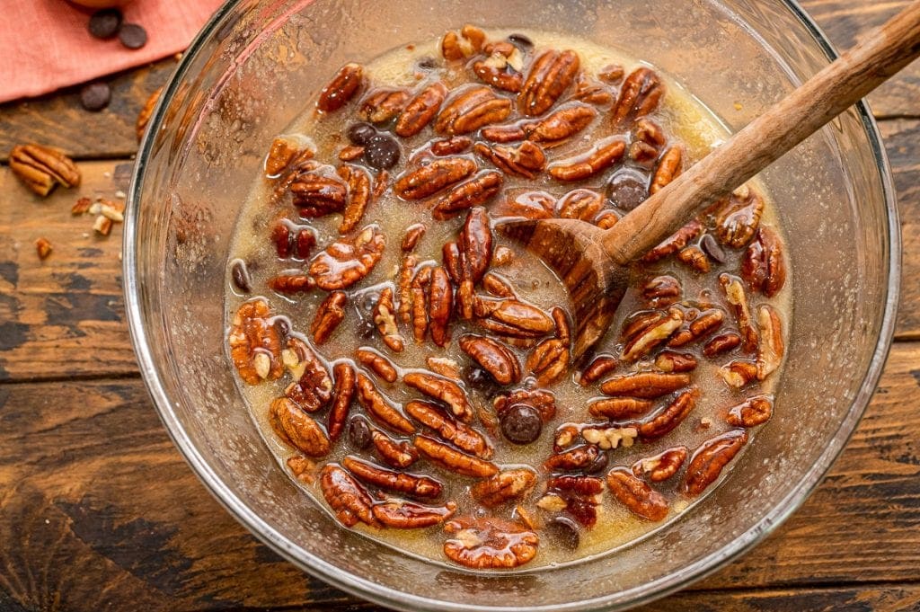 Glass bowl with pecan pie filling mixed together.