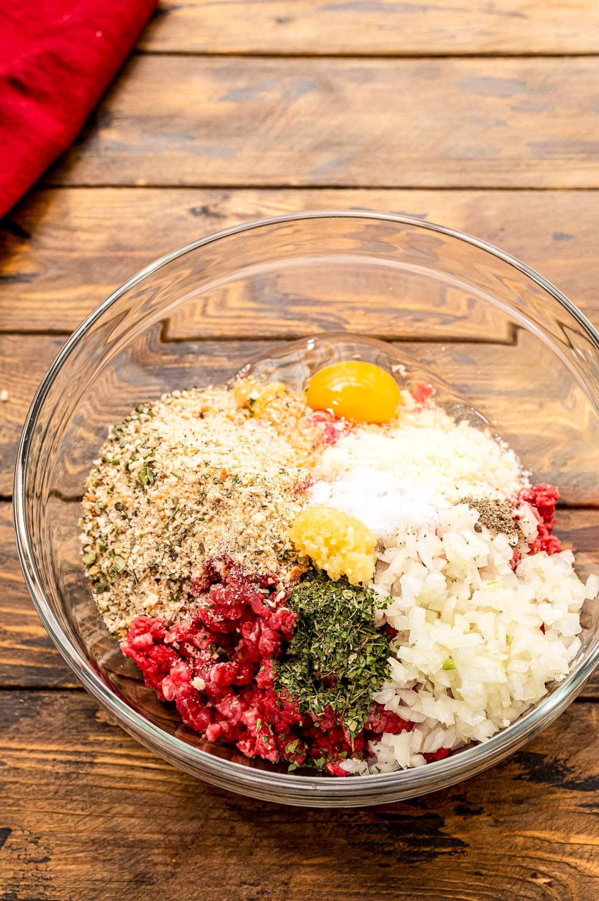 Glass bowl with ingredients before mixing to make homemade meatballs