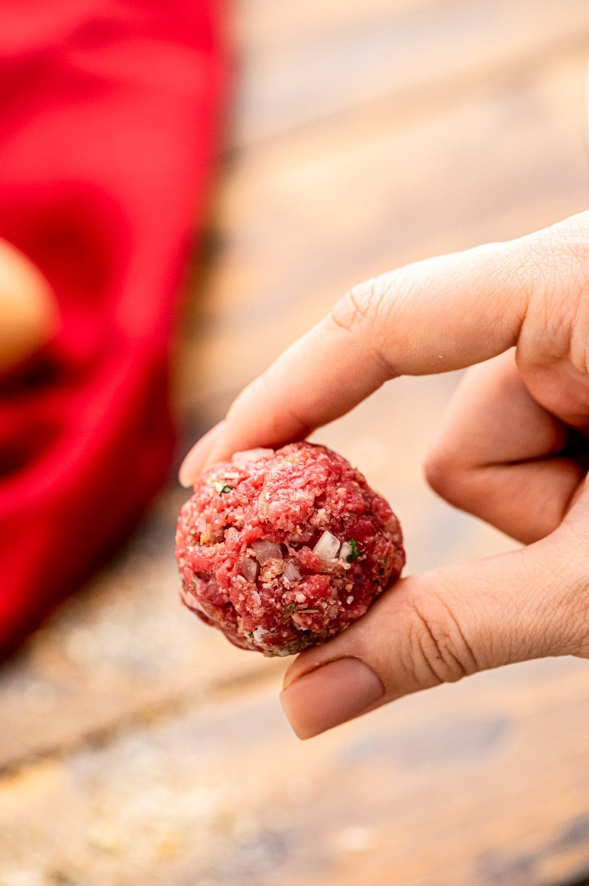 Two fingers holding raw homemade meatball