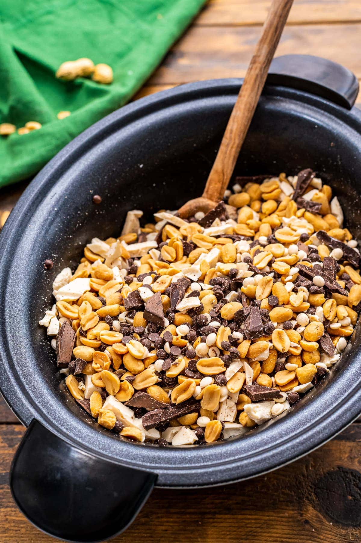 Crock Pot with ingredients for peanut clusters stirred together.