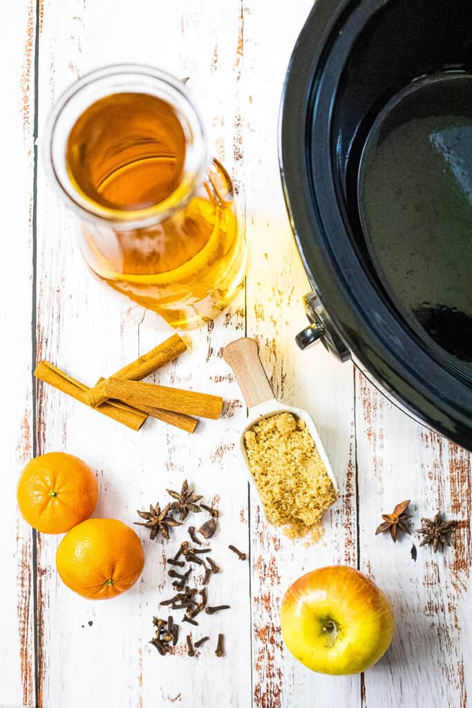 Crock pot next to apple cider, oranges, brown sugar, apple juice etc to make spiked apple cider