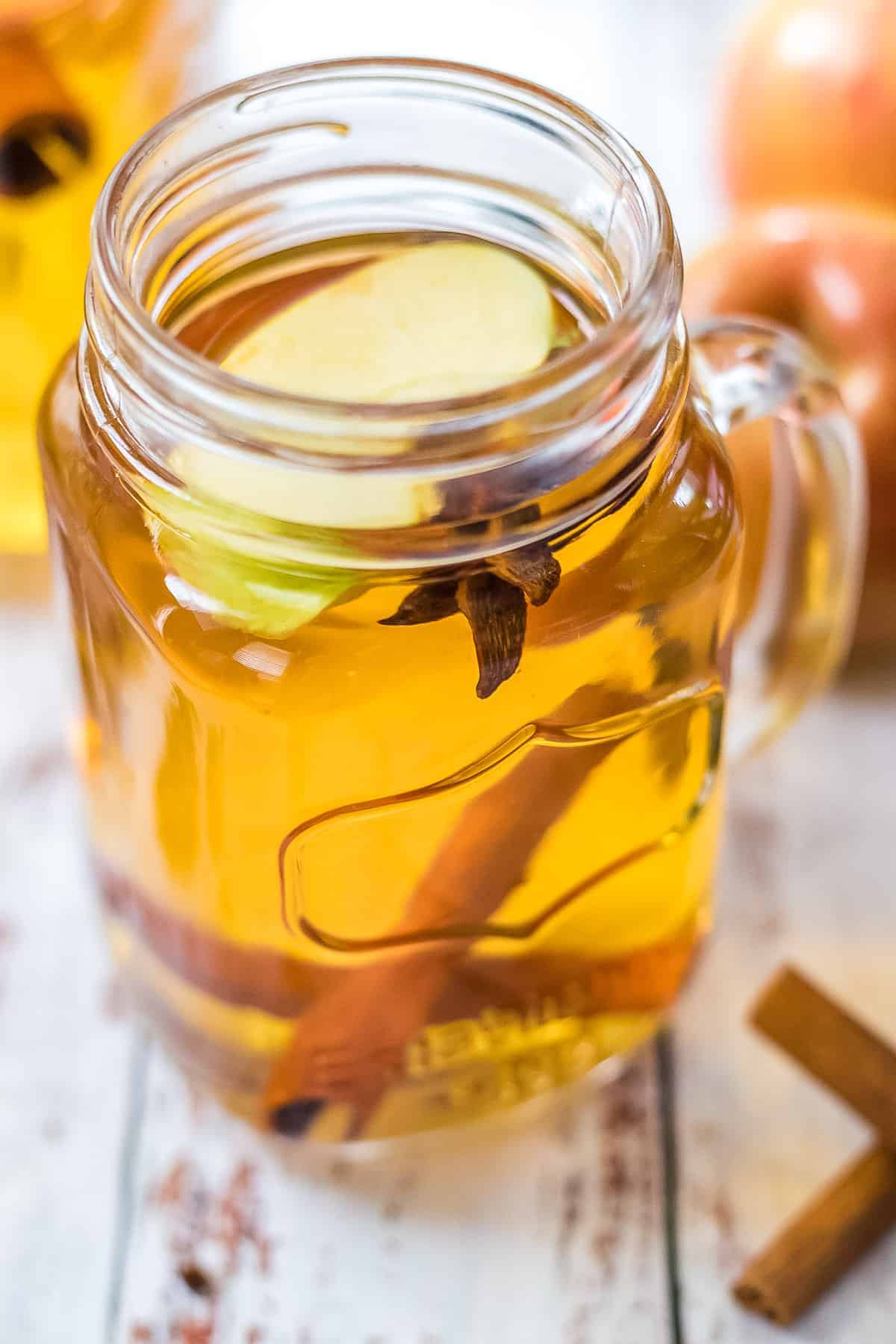 Close up photo of spiked apple cider in glass mason jar mug