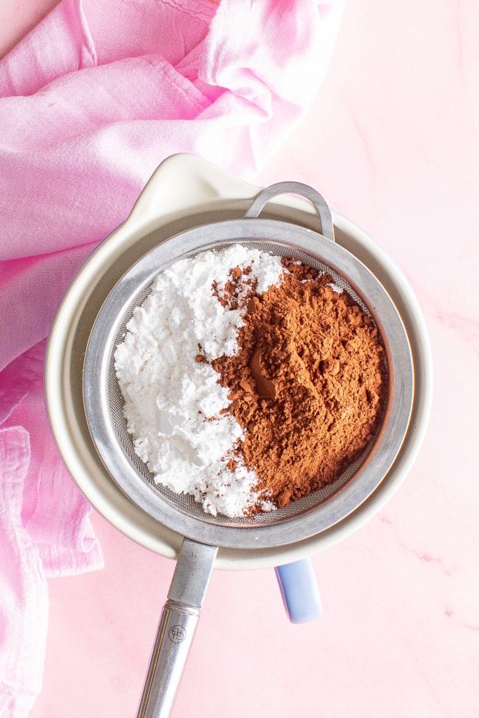 Sifter over a bowl with powdered sugar and cocoa in it