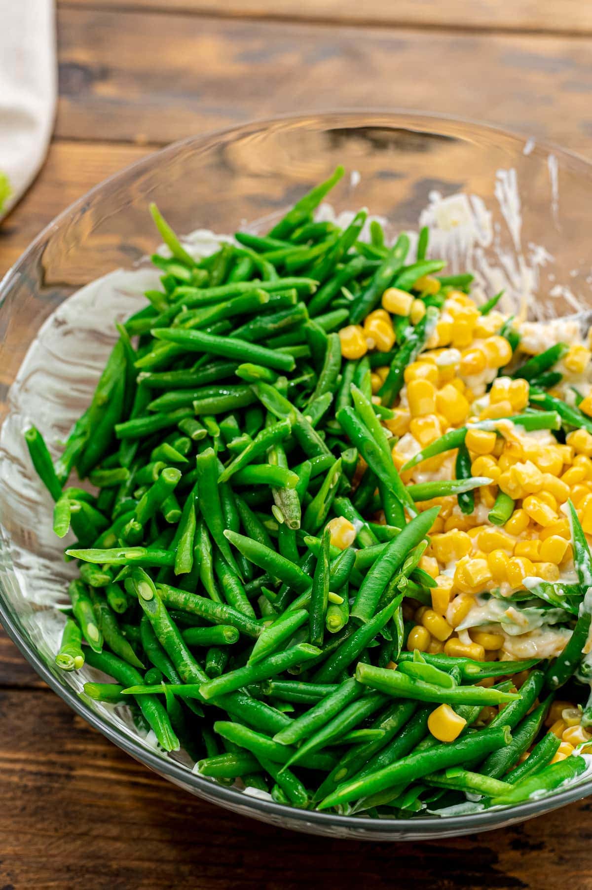 Glass bowl with corn and green beans added to soup mixture for casserole