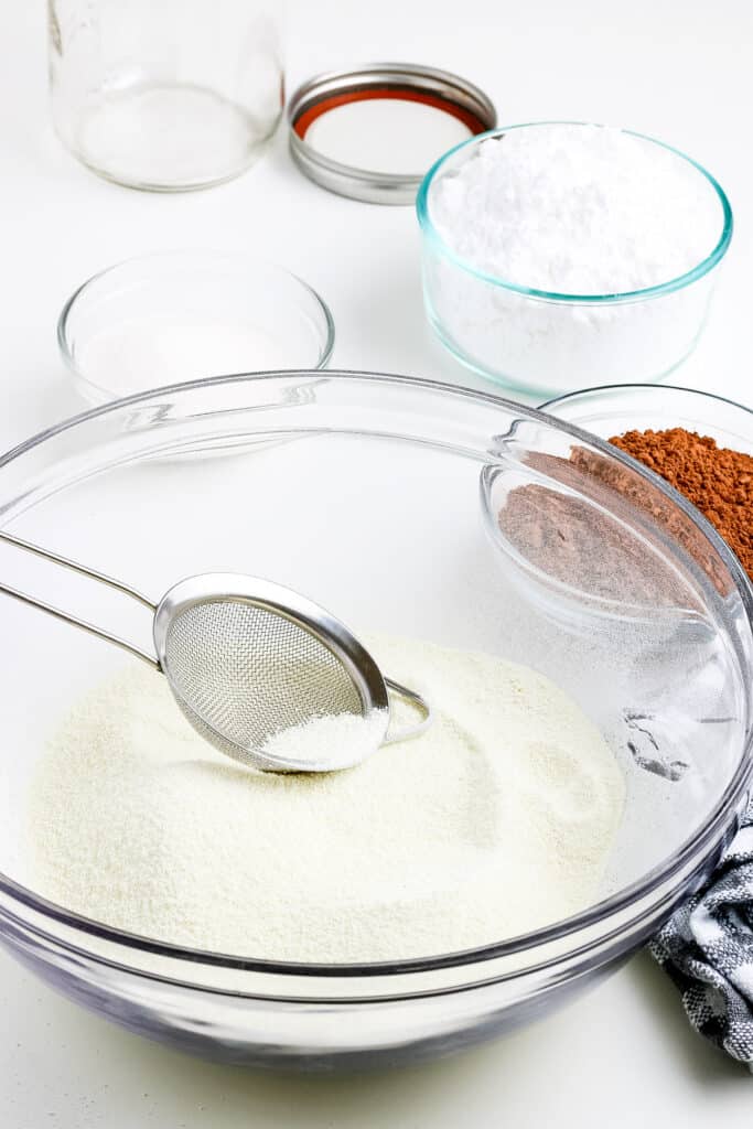 Glass bowl with powdered milk and sift sitting in it