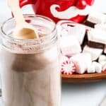 Hot Chocolate Mix in glass jar with a little scoop and festive decor in background