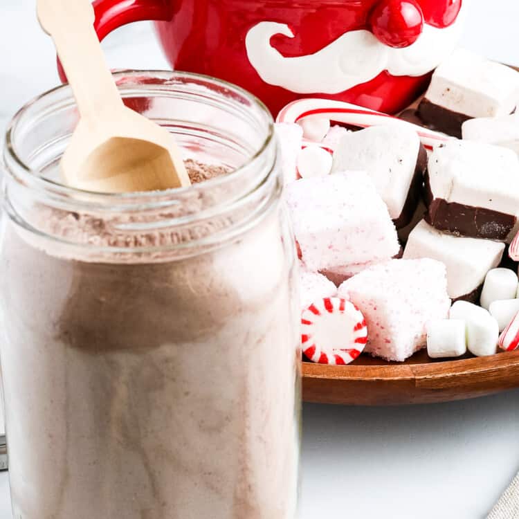 Hot Chocolate Mix in glass jar with a little scoop and festive decor in background