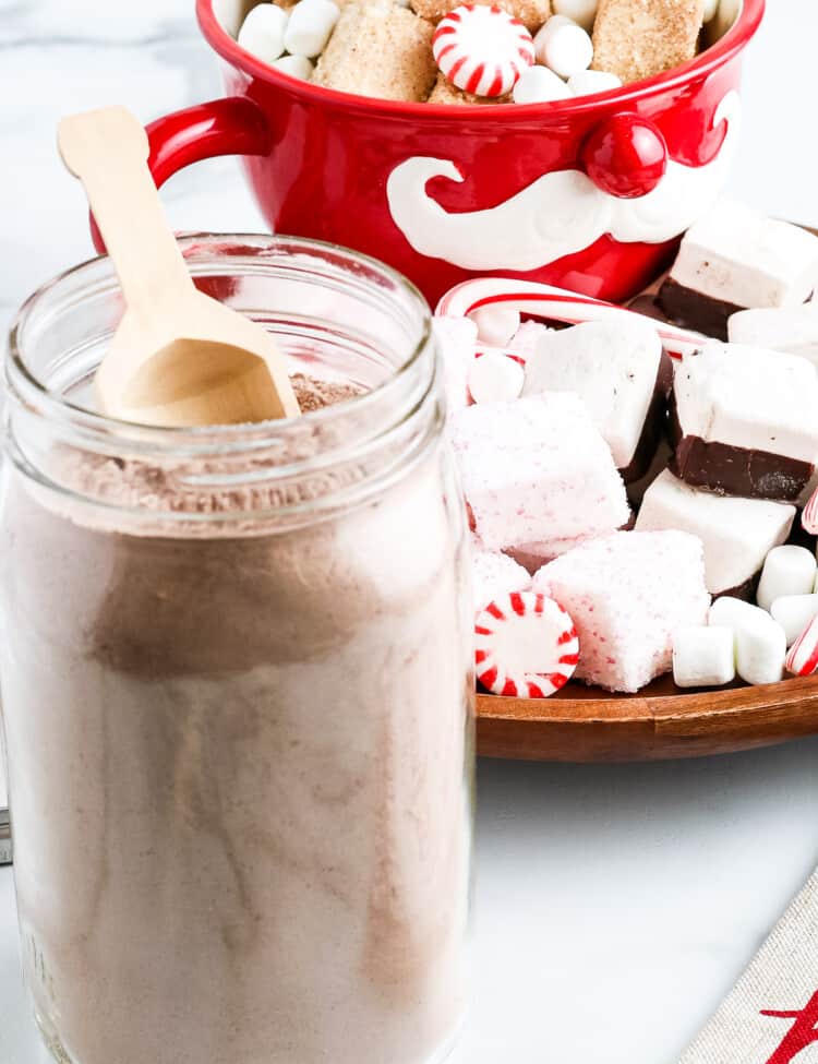 Hot Chocolate Mix in glass jar with a little scoop and festive decor in background
