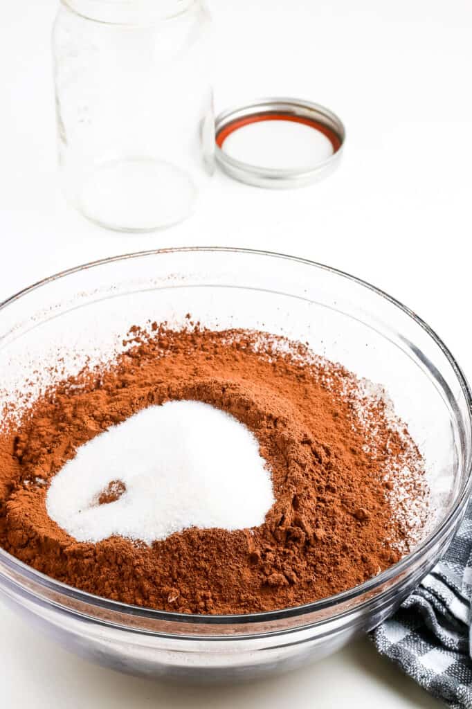 Glass bowl with cocoa powder with sugar on top.