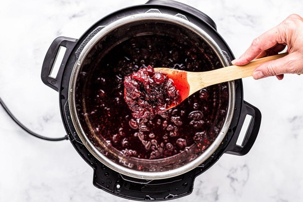 Spoon with Instant Pot cranberry sauce on it over the instant pot.