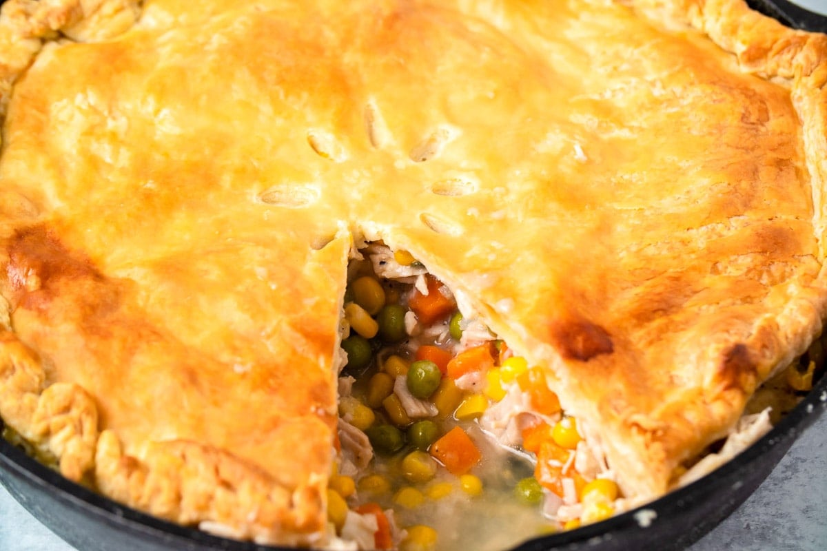 Turkey pot pie in cast iron skillet with slice taken out.