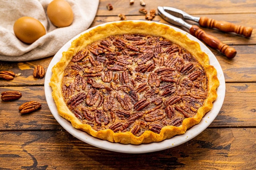 Pecan Pie in a white baking dish on wood background