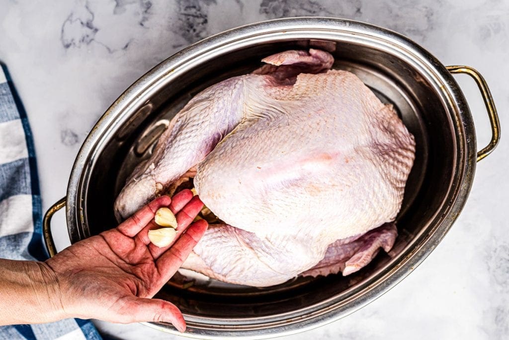 Roast Turkey in Pan with garlic being added to cavity