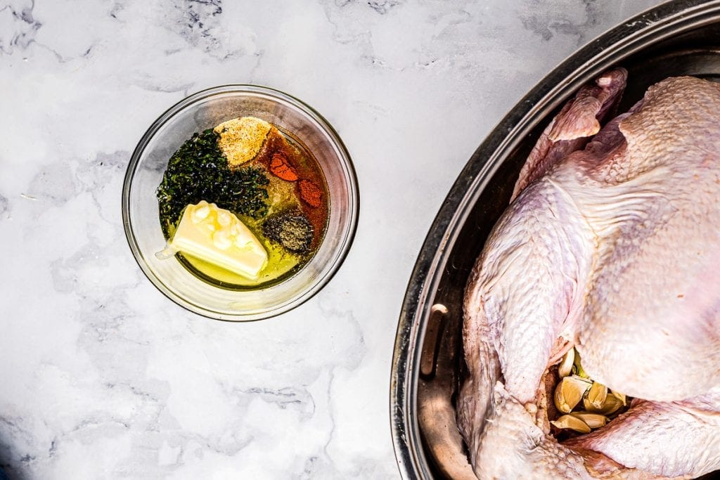 Roast Turkey in Pan with a bowl of seasonings next to it before being mixed