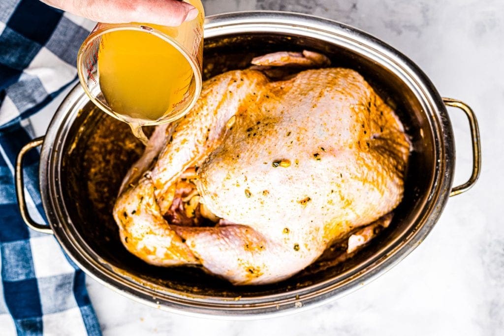 Chicken broth being added to pan with turkey
