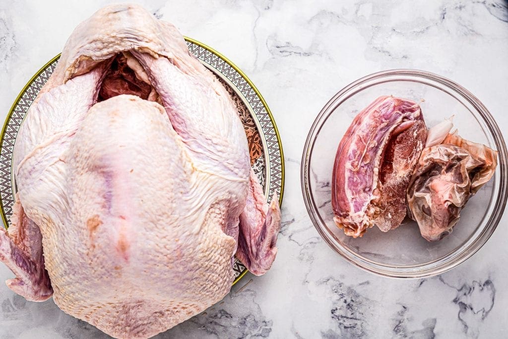 Turkey with next and giblets removed and next to it in bowl