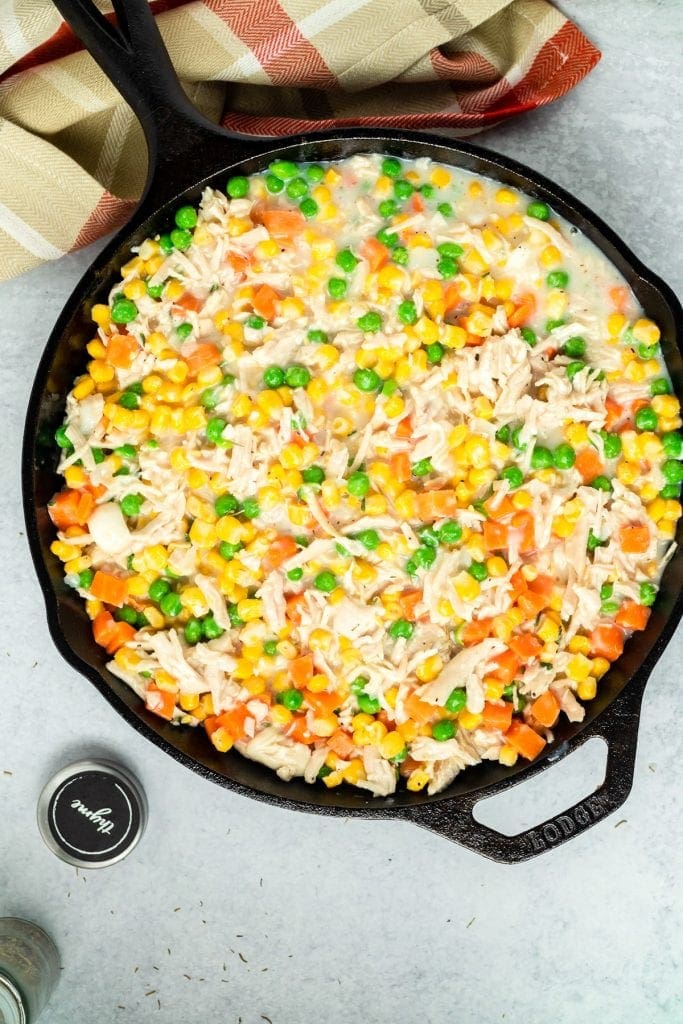 Filling for turkey pot pie poured into cast iron skillet.