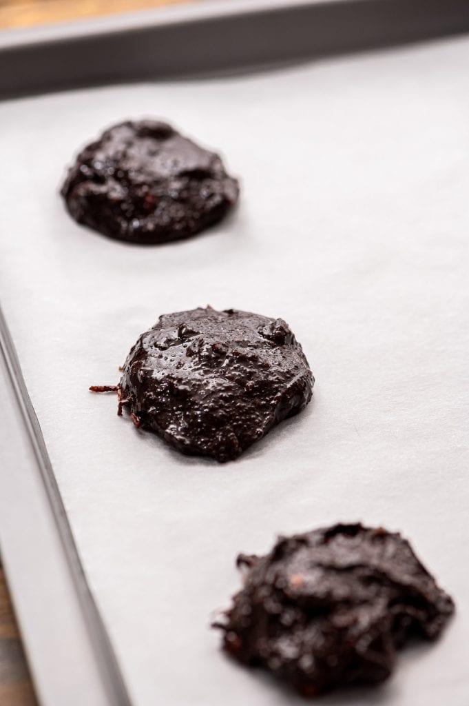 Chocolate Cookies dropped onto parchment paper on baking sheet before baking.