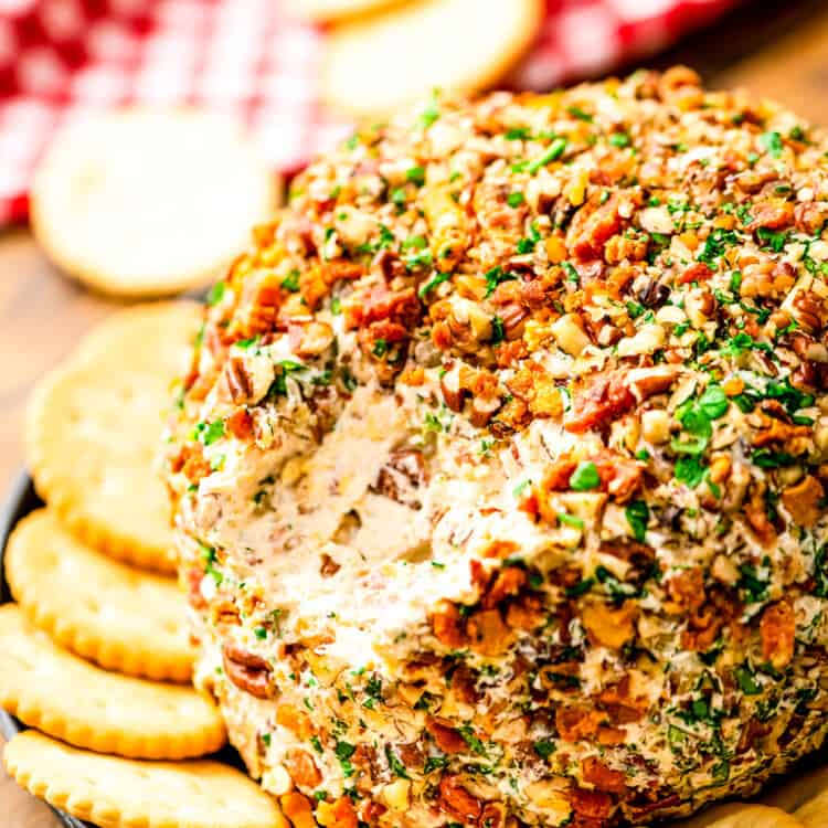 Bacon Ranch Cheese Ball with a scoop taken out of it on plate with crackers