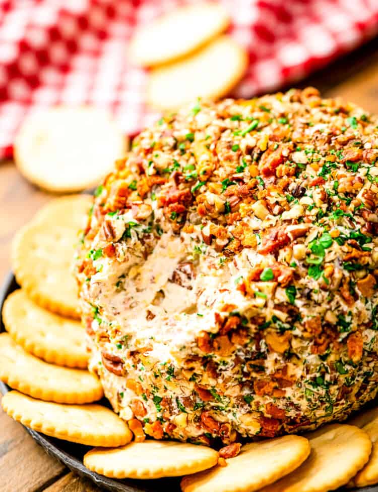 Bacon Ranch Cheese Ball with a scoop taken out of it on plate with crackers