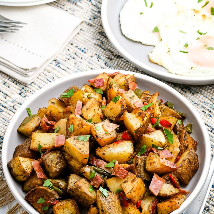 White plate with a dish of breakfast potatoes on it.