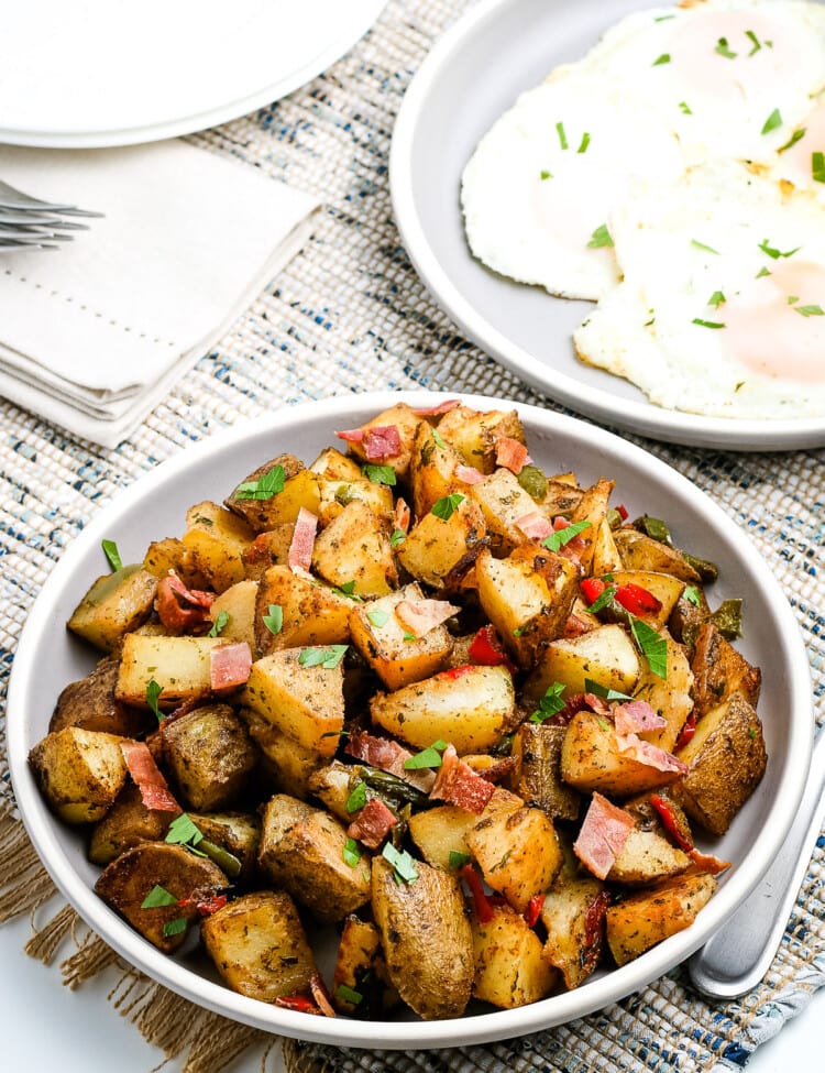 White plate with a dish of breakfast potatoes on it.