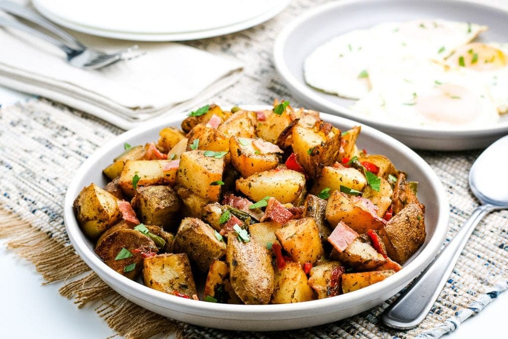 Breakfast Potatoes on a white dish with a spoon laying next to it.