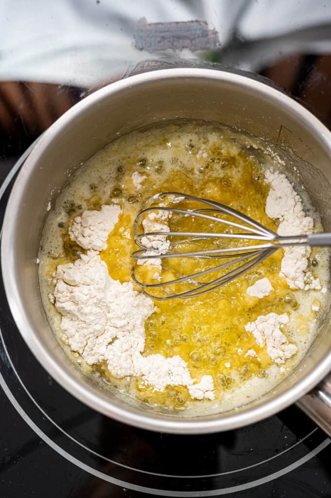 Whisk mixing together flour and broth in saucepan