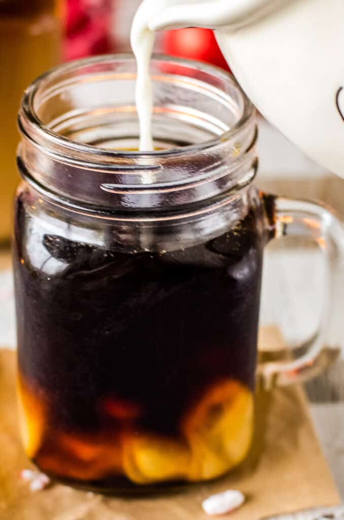 Glass mug of Christmas Coffee with milk being poured in it