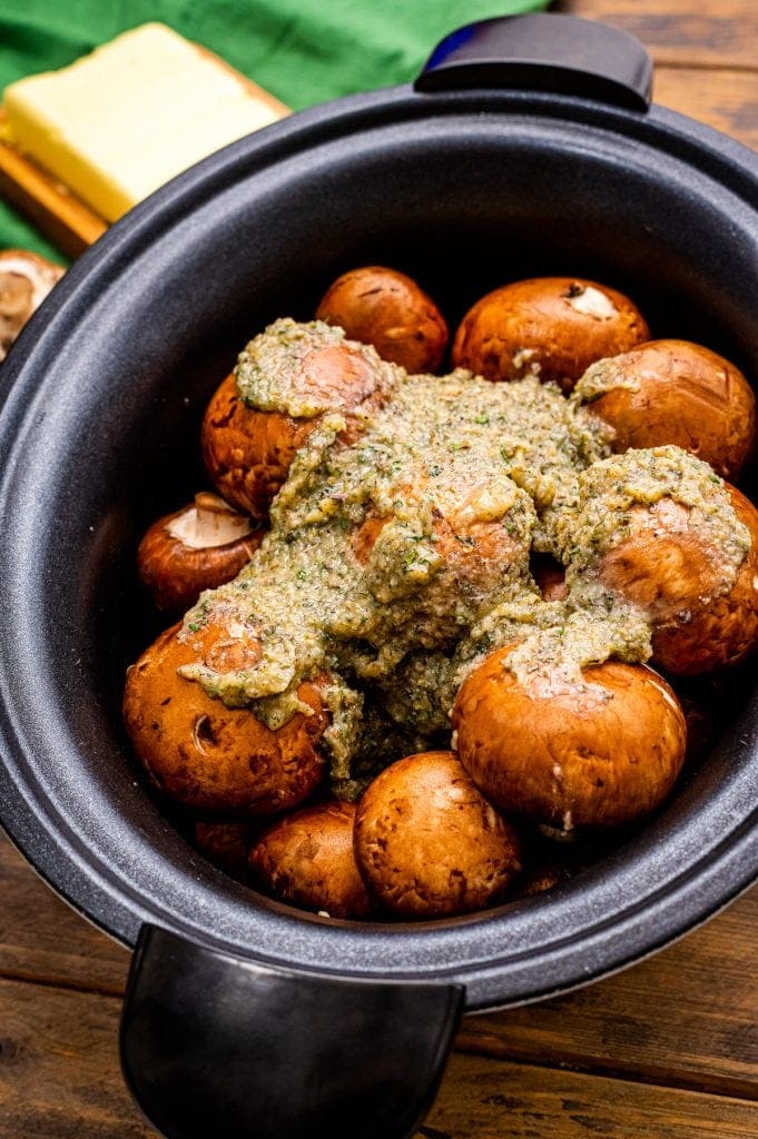 Crock Pot with mushrooms in it with butter poured over them.