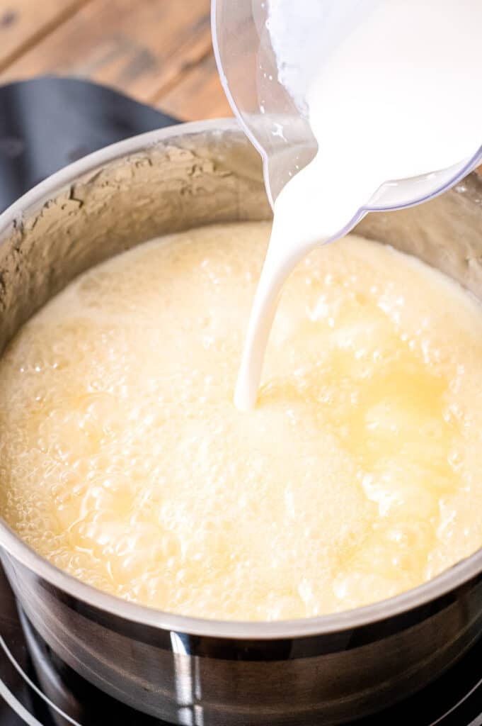 Pouring heavy cream into mixture in saucepan for caramels