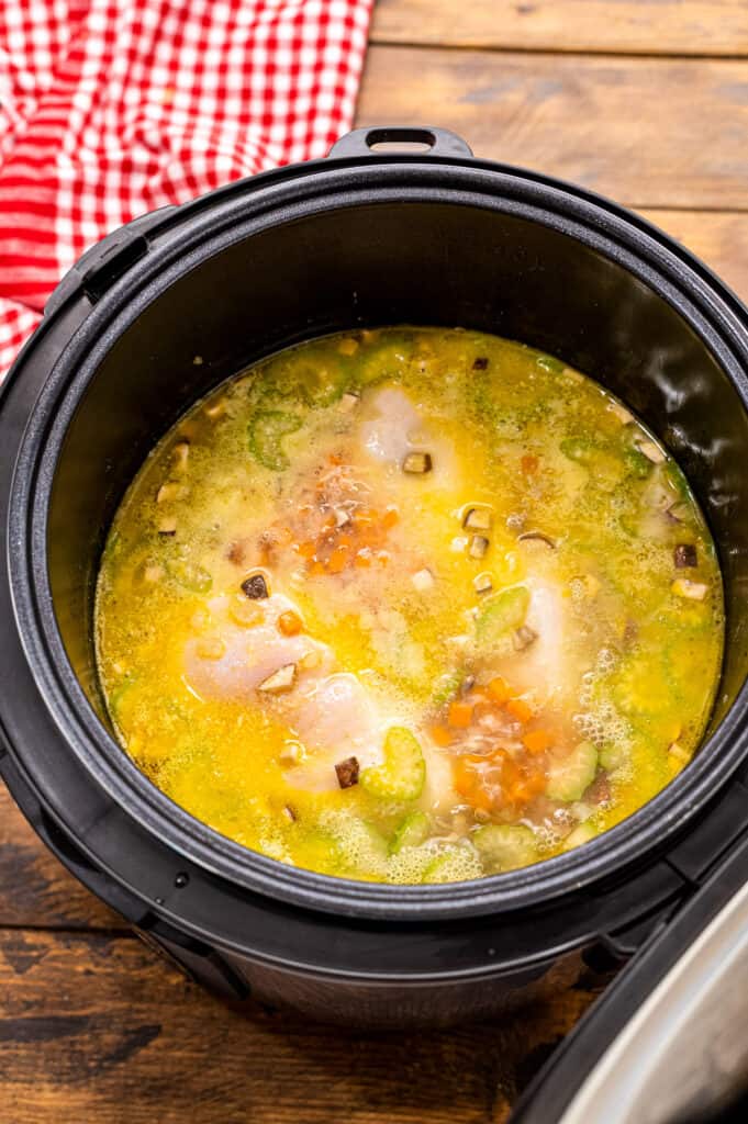 Instant Pot with ingredients for chicken wild rice soup with broth poured over them.