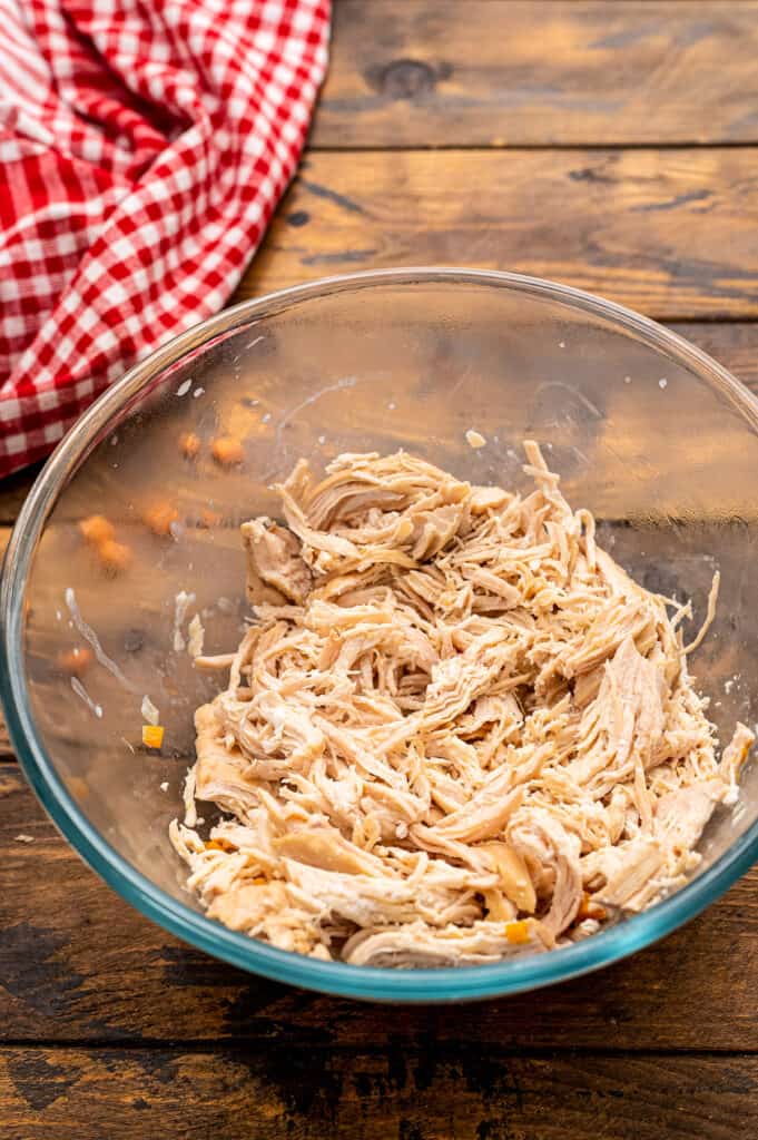 Glass bowl with shredded chicken in it.