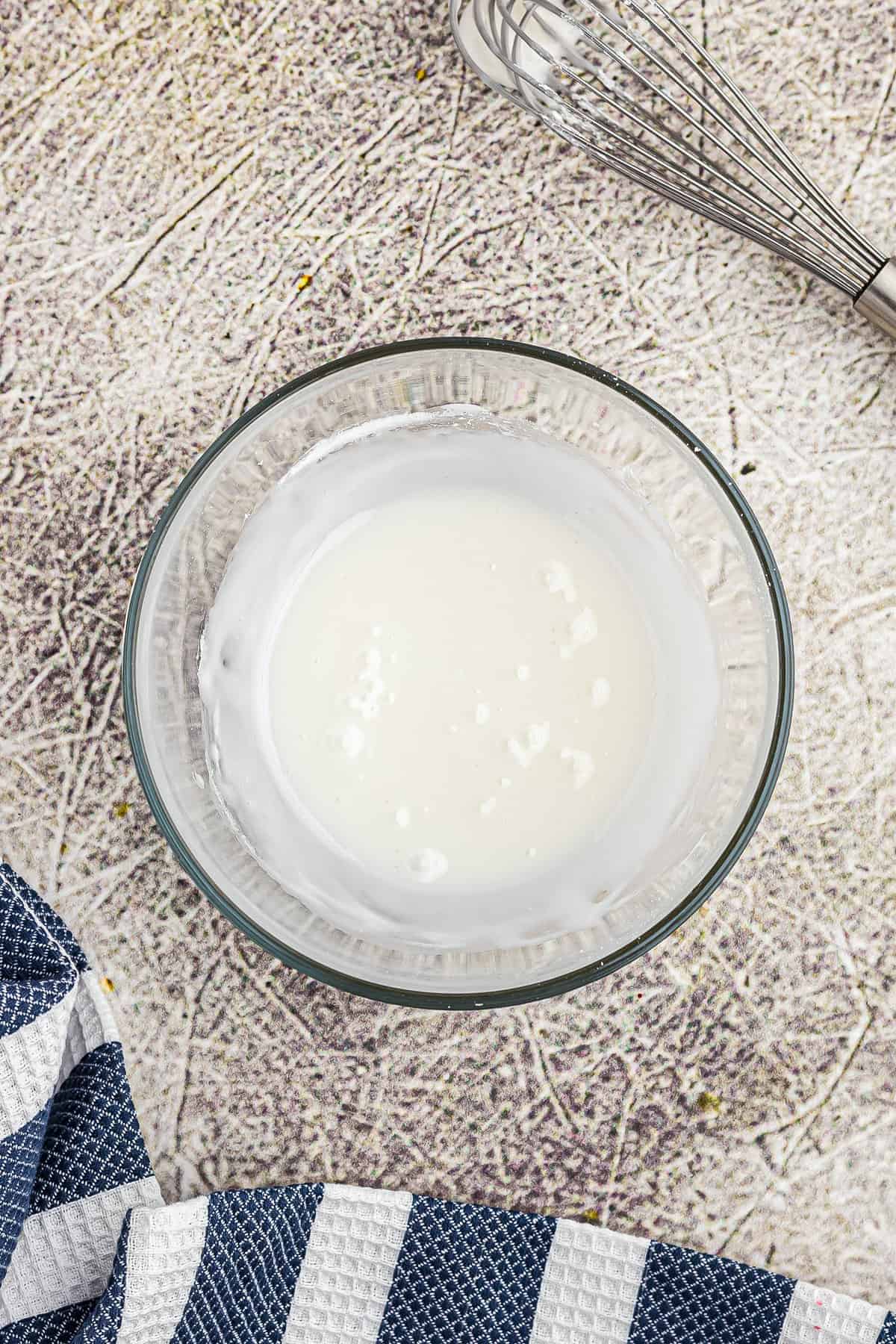 Glass bowl with powdered sugar and milk in it after mixing.