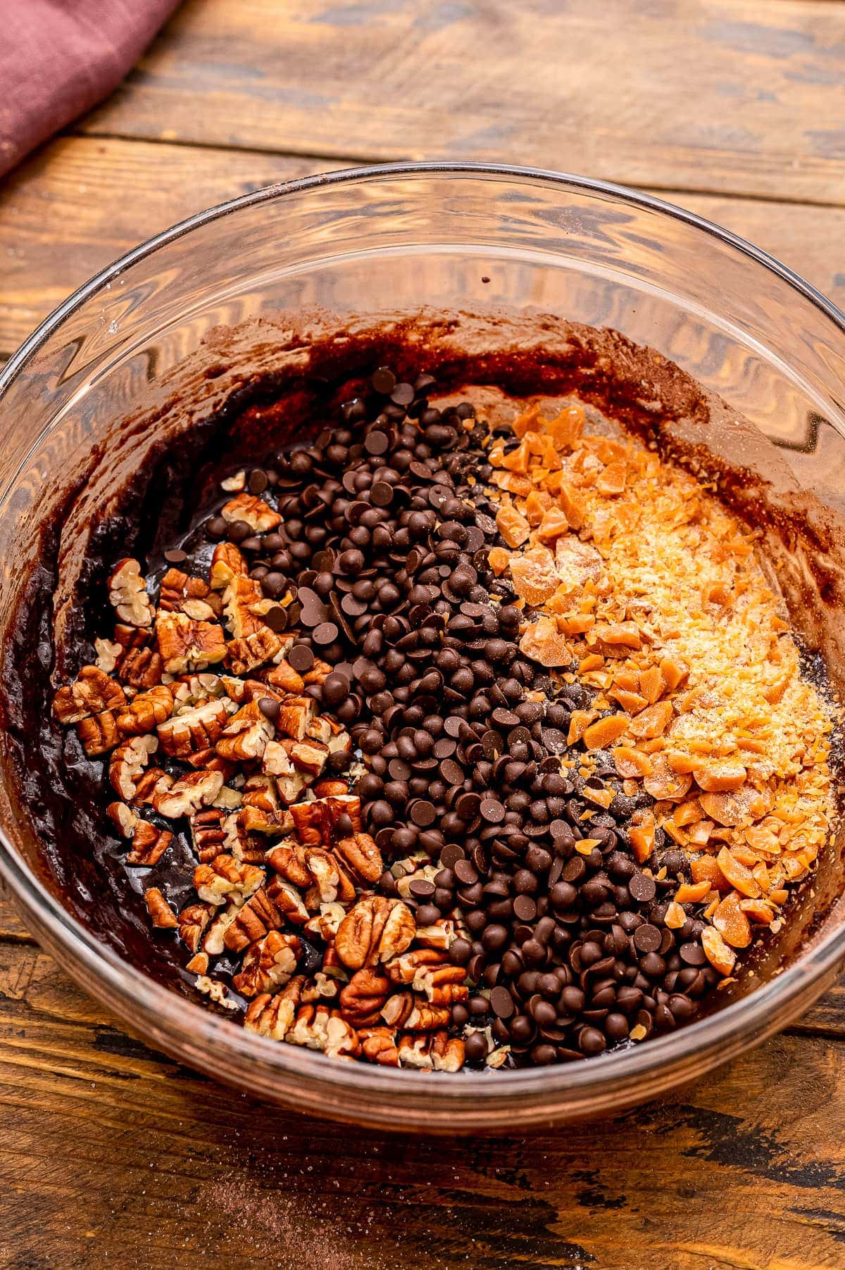 Glass bowl with turtle brownie ingredients before mixing.