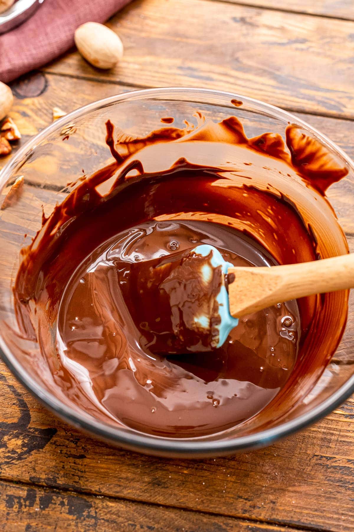 Glass bowl with spatula mixing up batter for brownies