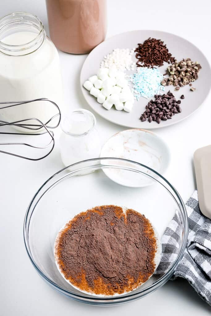 Glass bowl with heavy cream and hot chocolate mix before mixing.