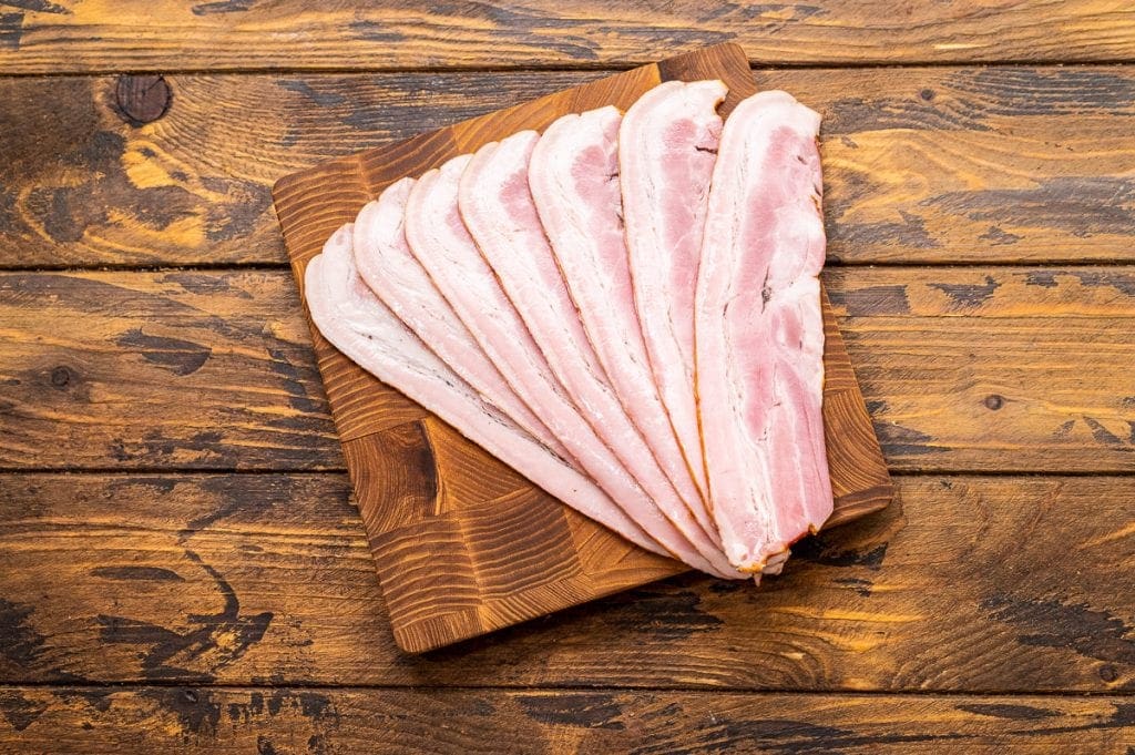 Bacon spread out on wood cutting board in fan shape