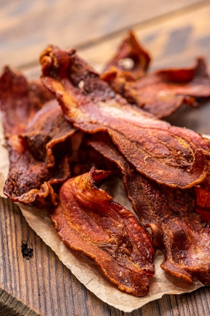 Pile of crispy bacon on top of wood cutting board