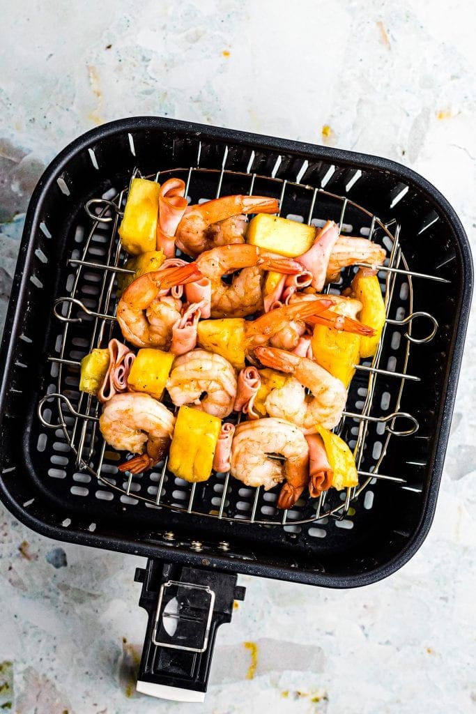 Air Fryer Basket with Hawaiian Shrimp Kabobs in it.