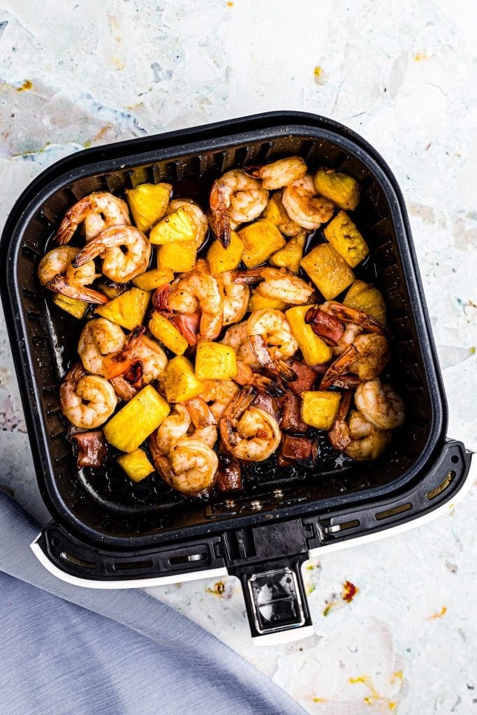 Air Fryer Basket with a mix of pineapple, shrimp and ham in a bbq sauce.