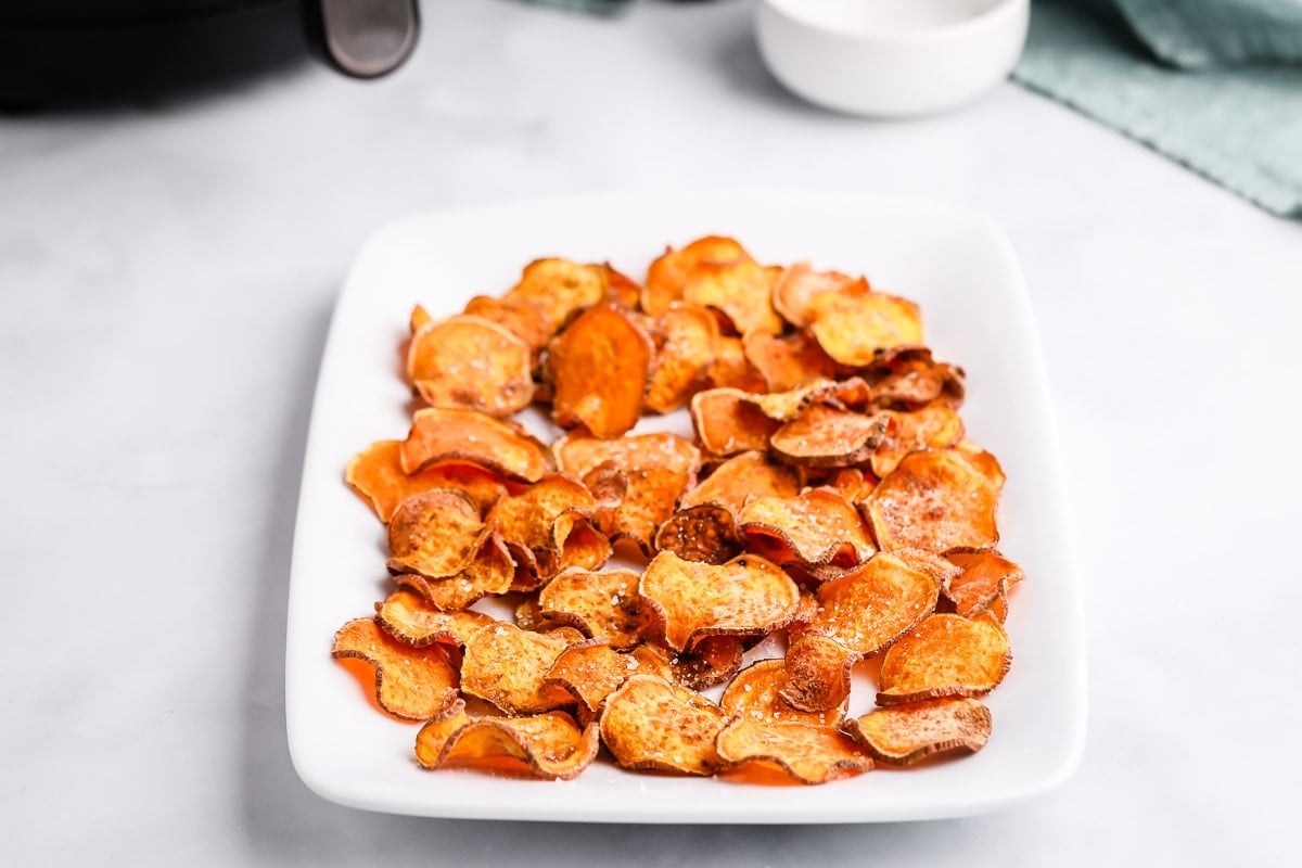 White platter of sweet potato chips seasoned with salt