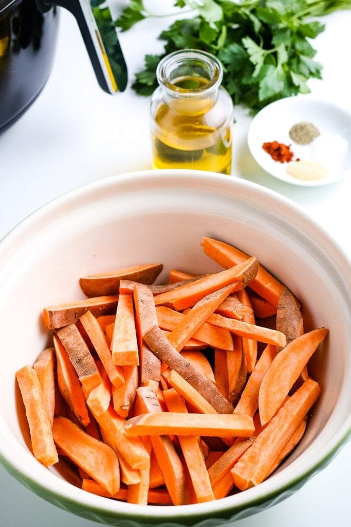 A ceramic bowl with sliced sweet potato fries in it.