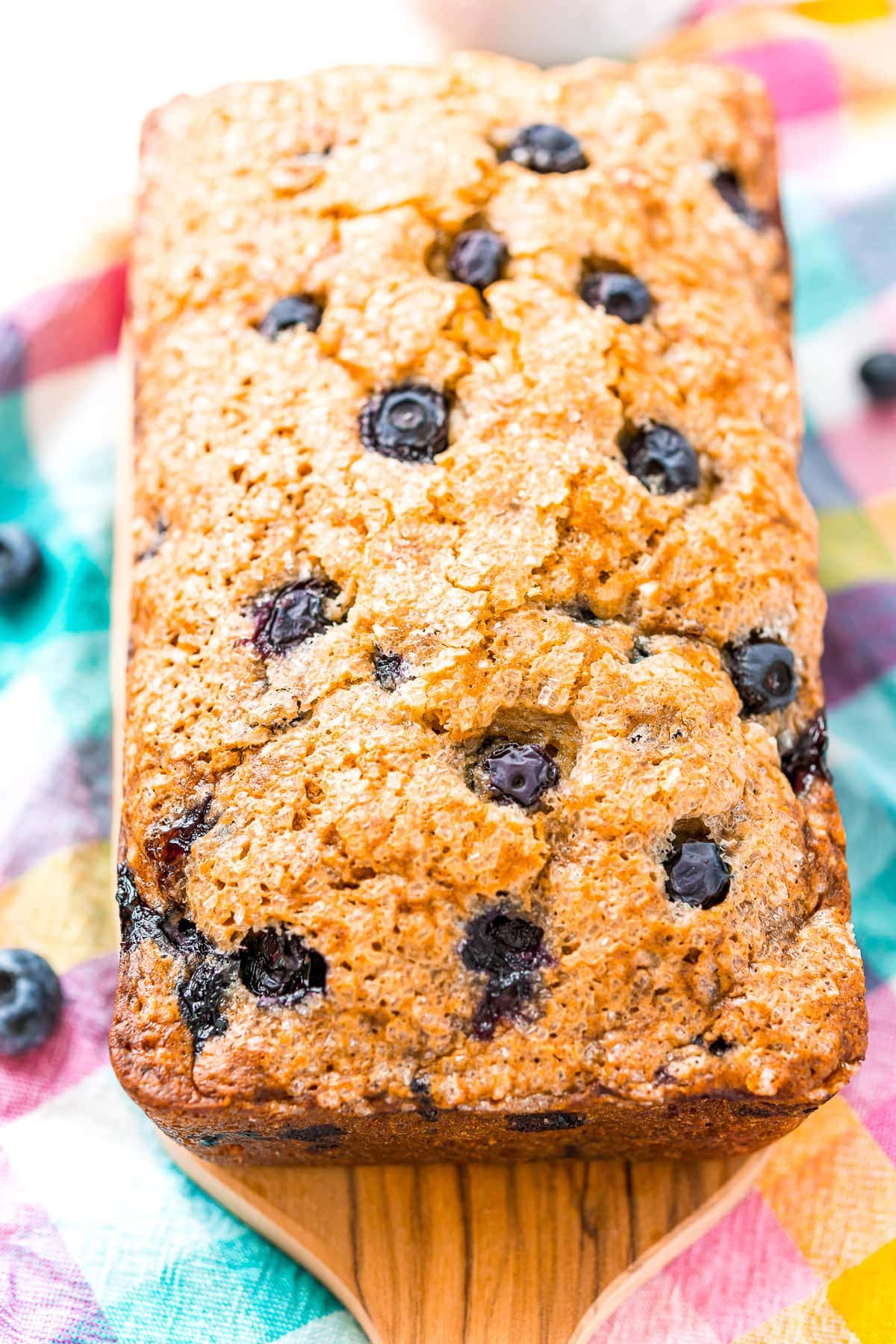 A loaf of baked Blueberry Banana Bread on wooden cutting board.