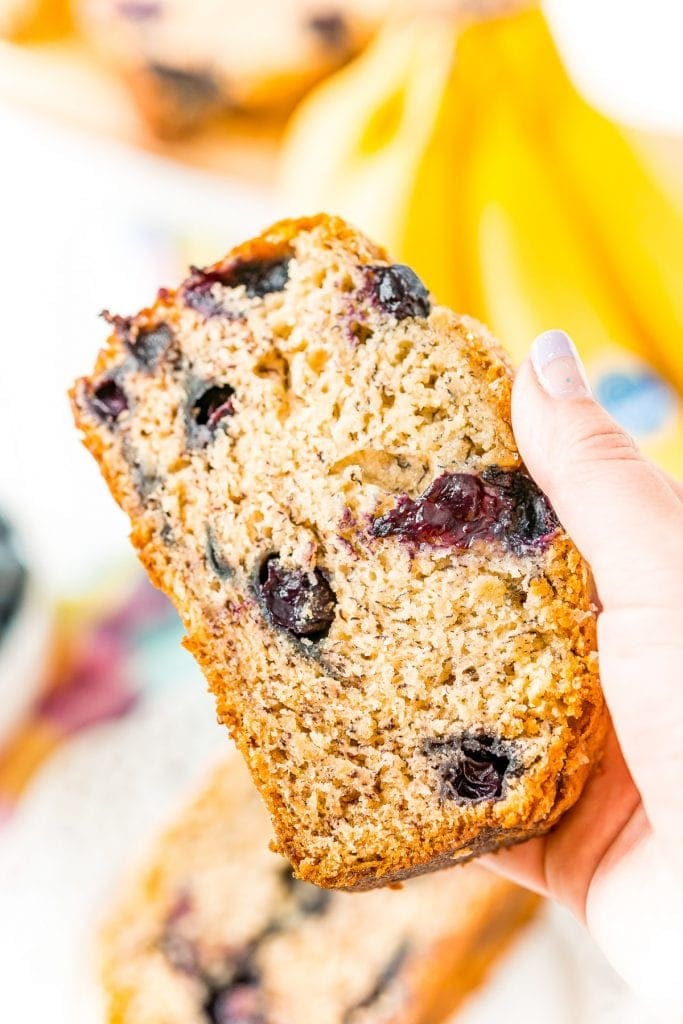 Hand holding a slice of Blueberry Banana Bread.