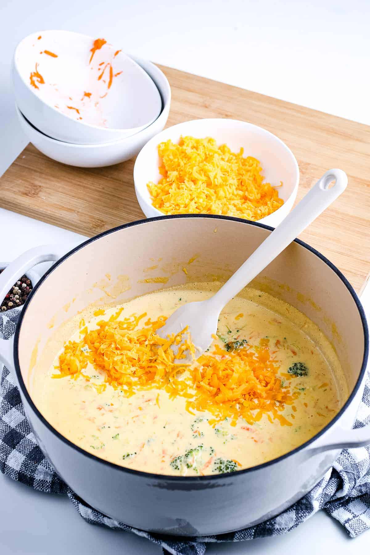 Dutch oven with soup base and shredded cheese before mixing together